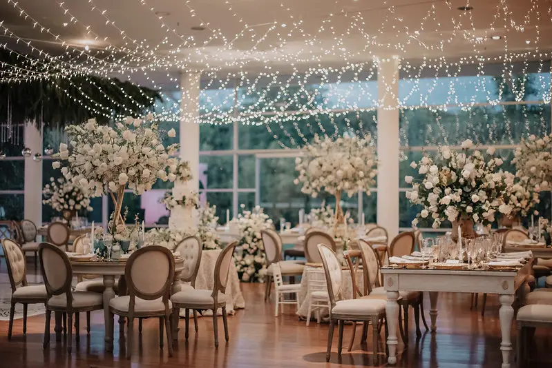 Montaje de mesa para invitados en salón de matrimonio Bogotá con centro de mesa de rosas blancas 