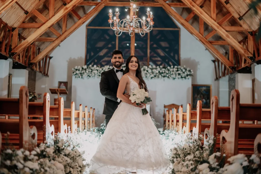 Pareja de recien casados en una Capilla decorada con flores blancas felices por su boda