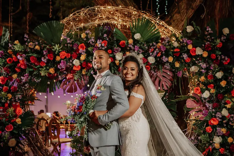 Pareja de recién casados sonriendo bajo un arco floral en su elegante recepción de bodas en Santa Marta.