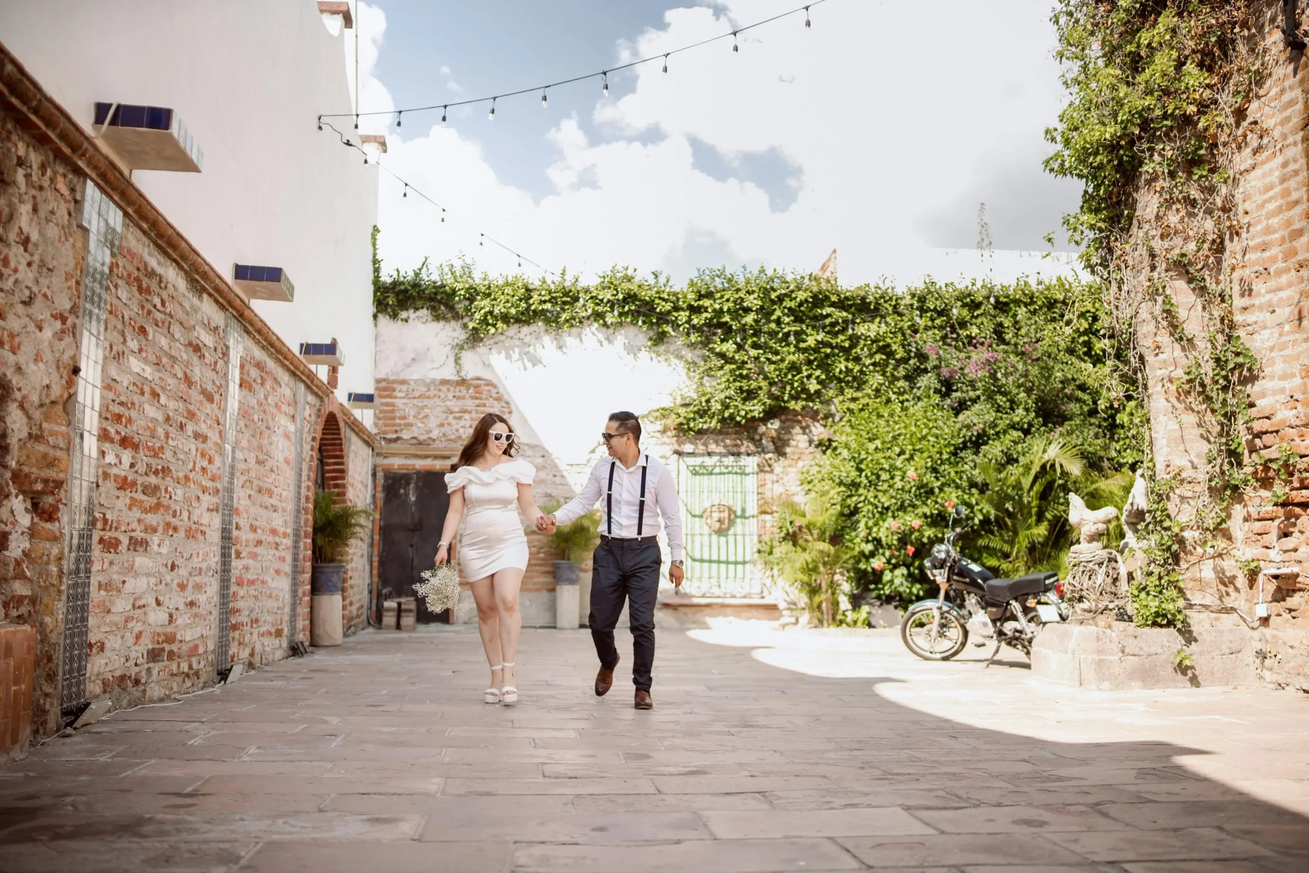 Pareja joven caminando de la mano por un patio o calle empedrada, celebrando su aniversario
