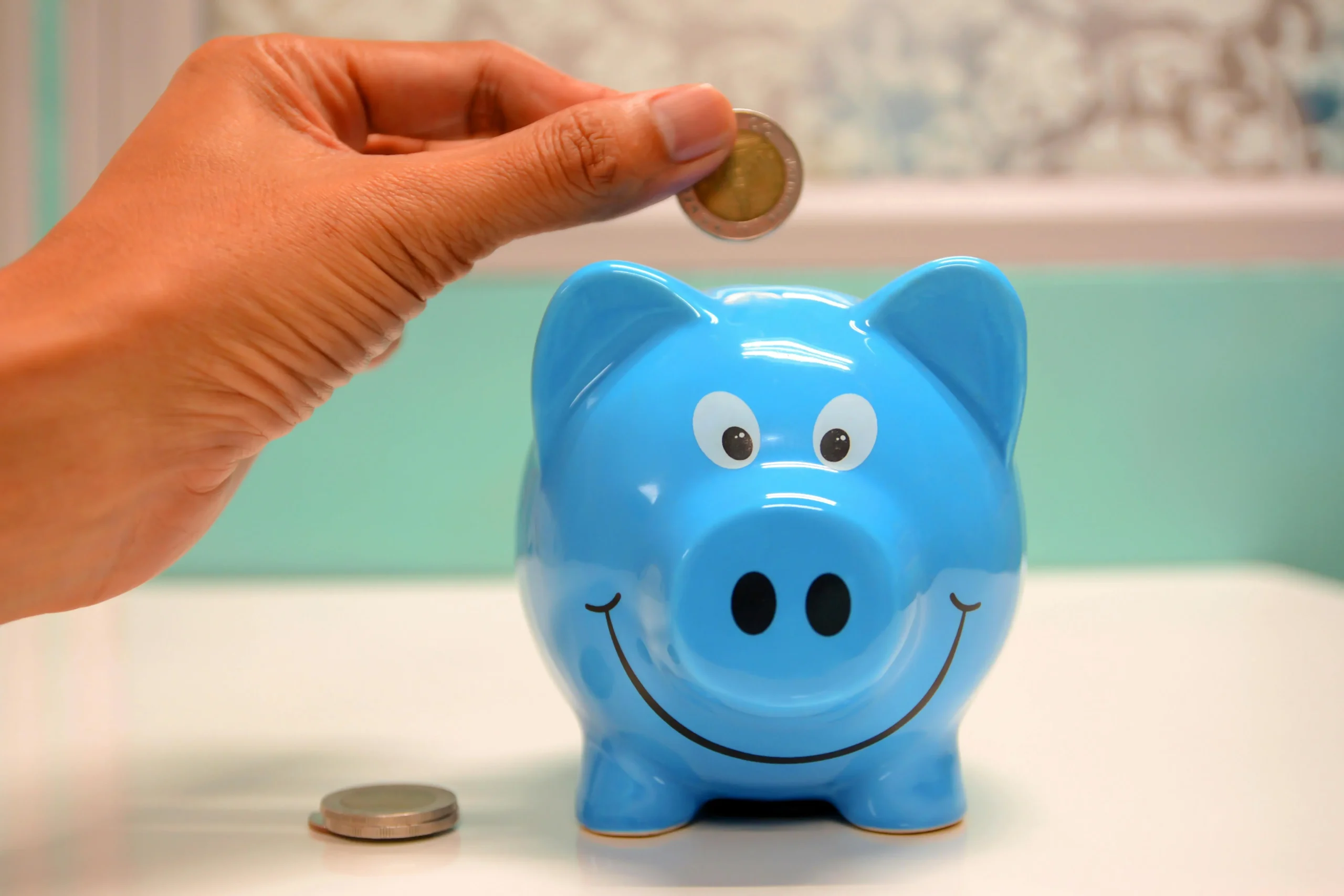 Mano depositando una moneda en una alcancía, simbolizando el presupuesto y costos de un matrimonio en Colombia