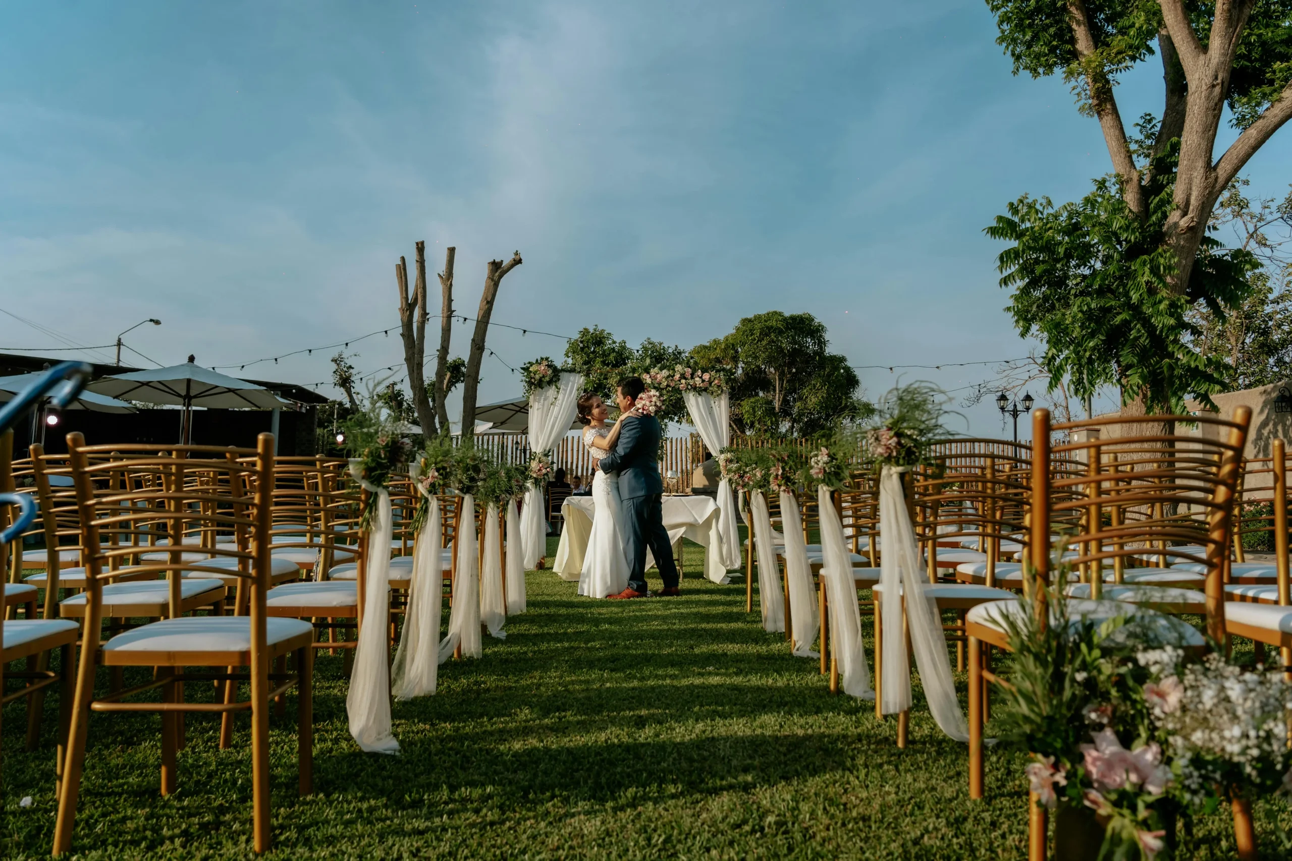 Montaje de ceremonia para una boda espiritual al aire libre en Colombia, mostrando el pasillo con sillas doradas decoradas y una pareja en el altar al fondo