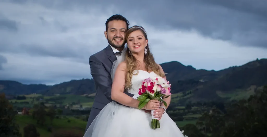 Novios felices posando para una foto de bodas en Guatavita, con las icónicas montañas y el paisaje campestre de la región de fondo.