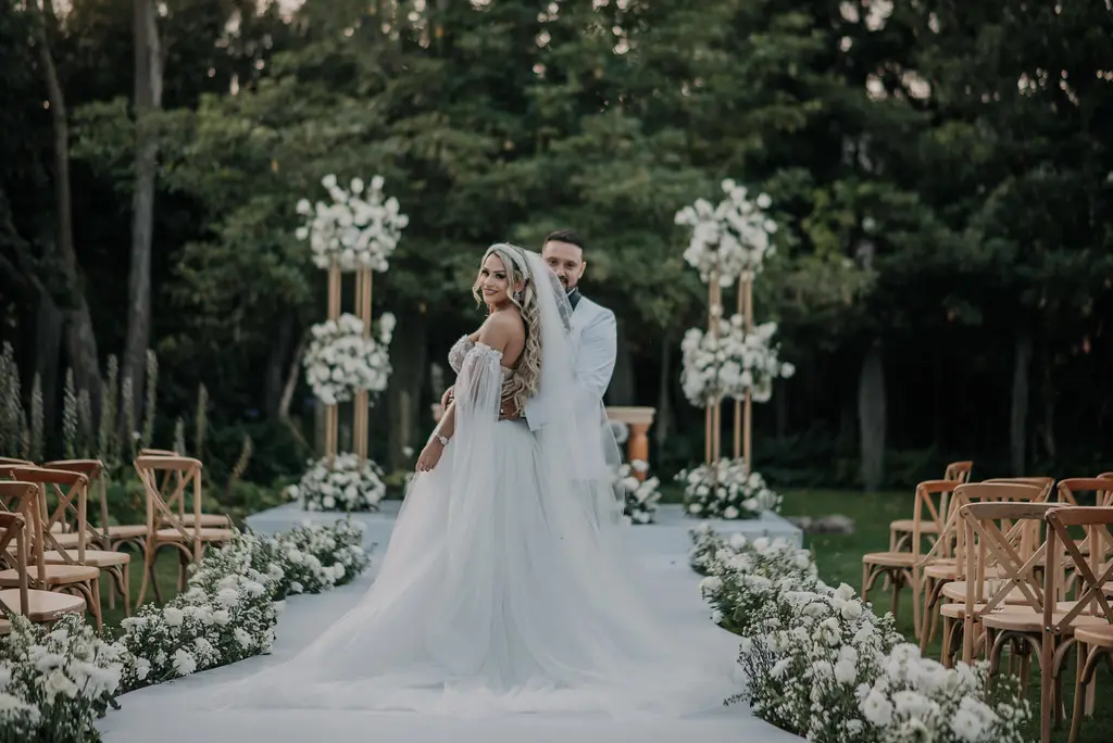 Vista completa de los novios en el altar de su boda, con la novia luciendo un espectacular vestido de falda amplia y velo largo
