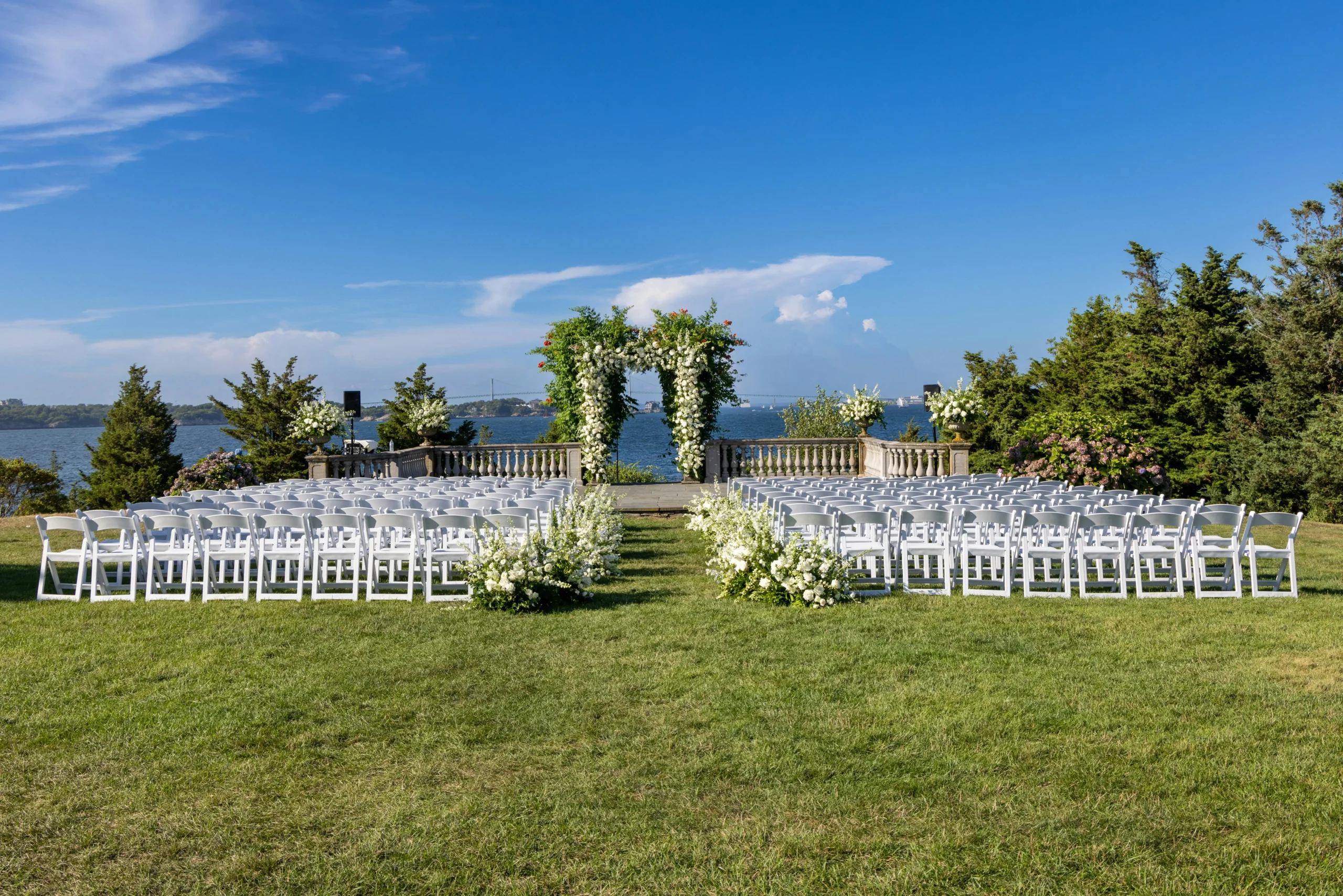 Espectacular montaje de ceremonia para bodas en Guatavita, con sillas blancas y un altar floral en un prado verde con vista panorámica al embalse.