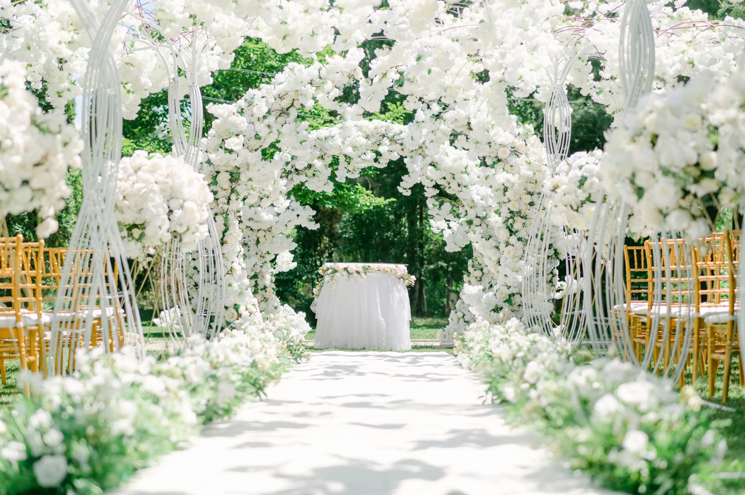 Pasillo de ceremonia para bodas en Guatavita, con un camino blanco y arcos completamente cubiertos de flores blancas que llevan a un altar.