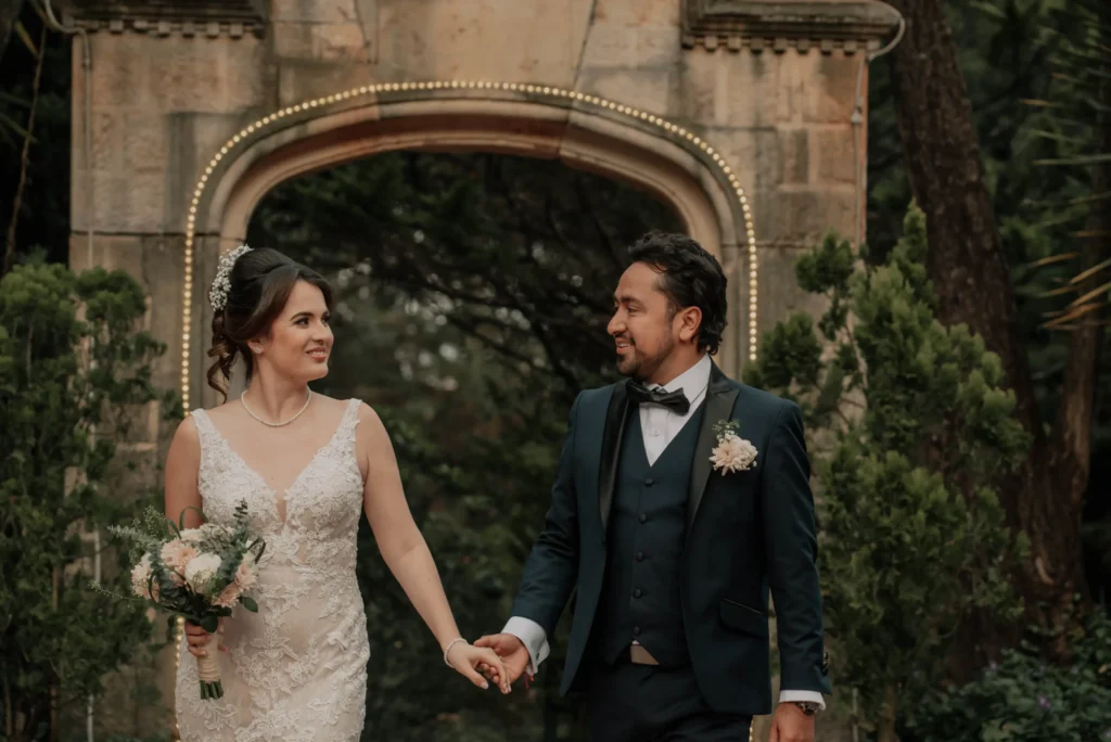 Pareja de recién casados caminando de la mano y sonriendo felices después de su ceremonia de boda campestre